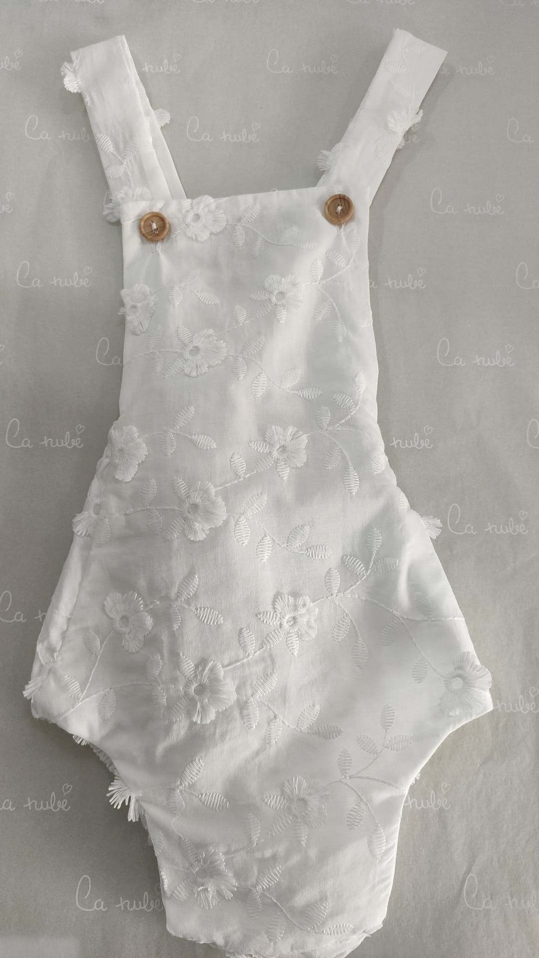 Un mono de encaje blanco para un bebé está sentado sobre una mesa.