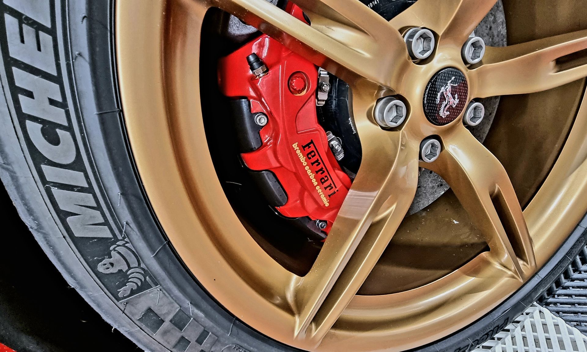 Jante de voiture dorée avec étrier de frein Ferrari rouge.