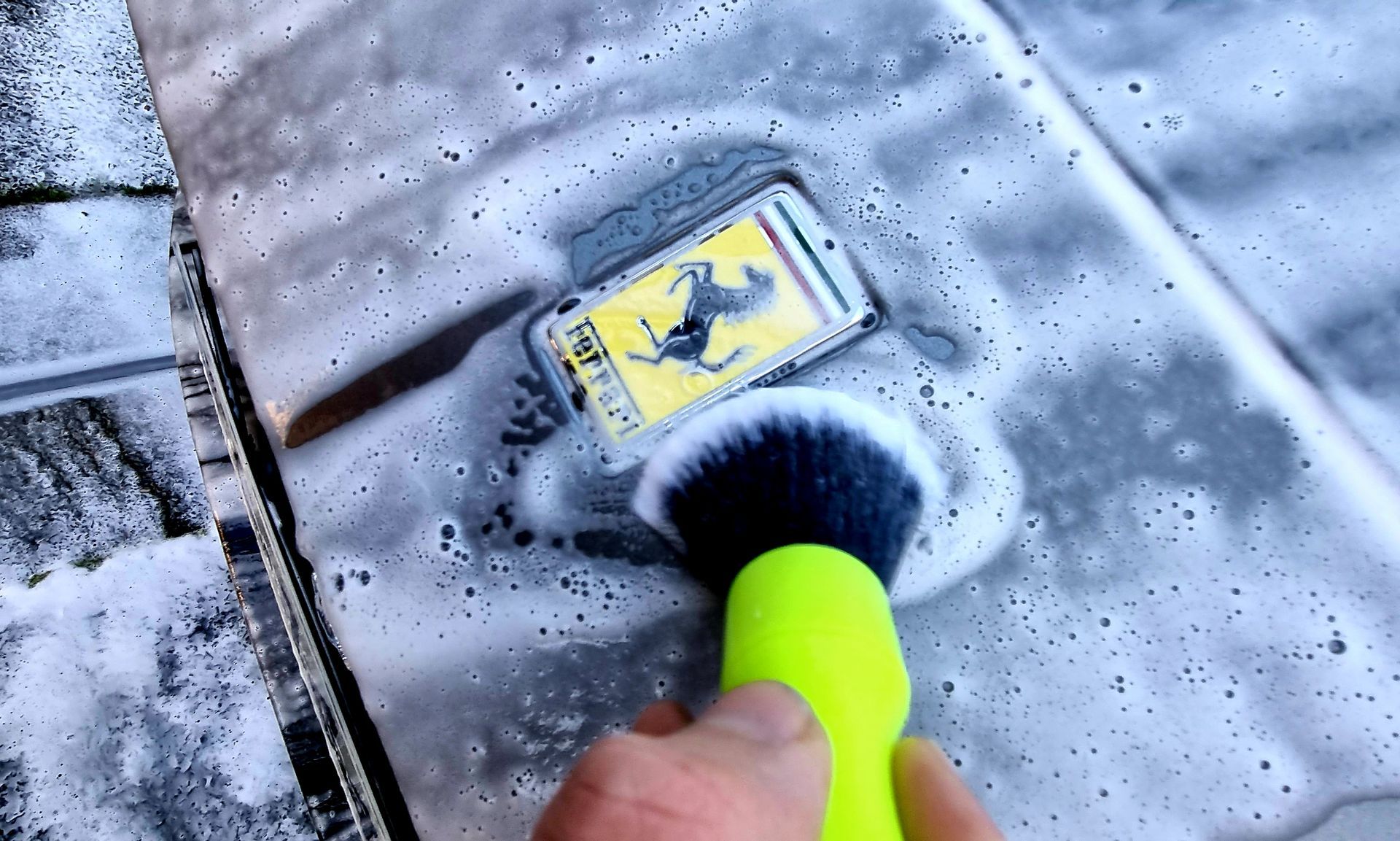 Un téléphone est lavé avec du savon et une brosse. L'écran affiche une image jaune.