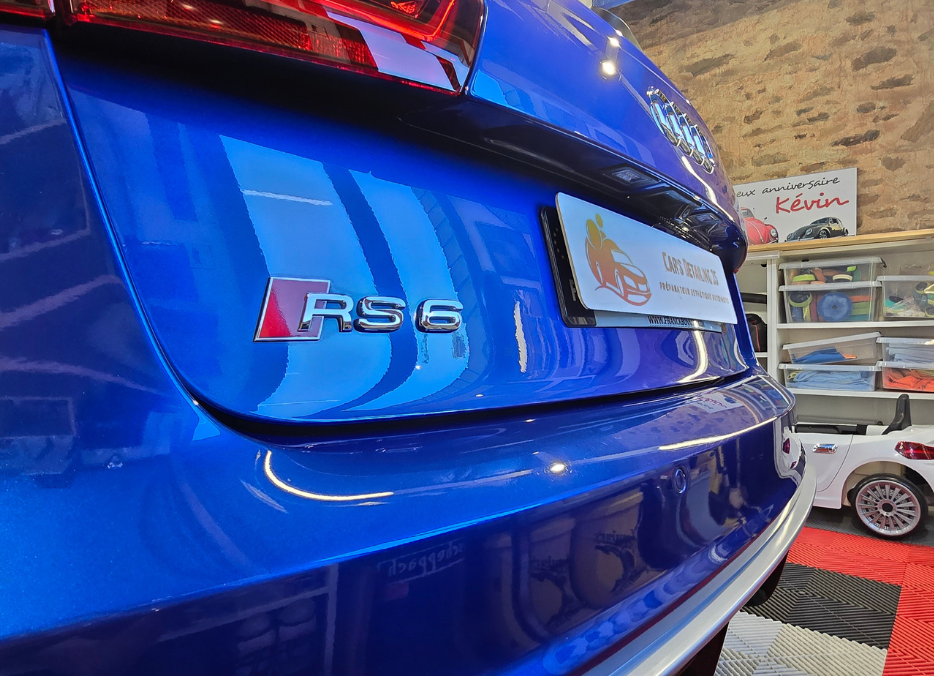 Détail arrière de l'Audi RS6 bleue, montrant le badge, dans un cadre de salle d'exposition.