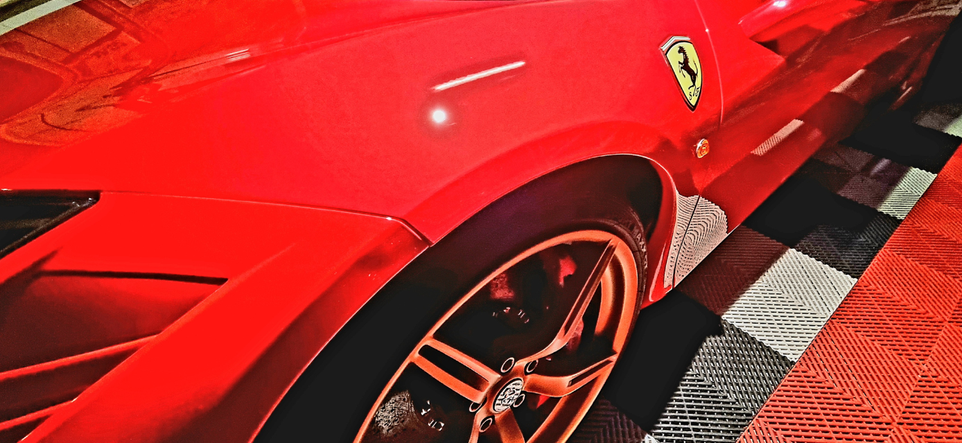 Voiture de sport Ferrari rouge avec un emblème jaune, un plancher à carreaux noir et blanc.