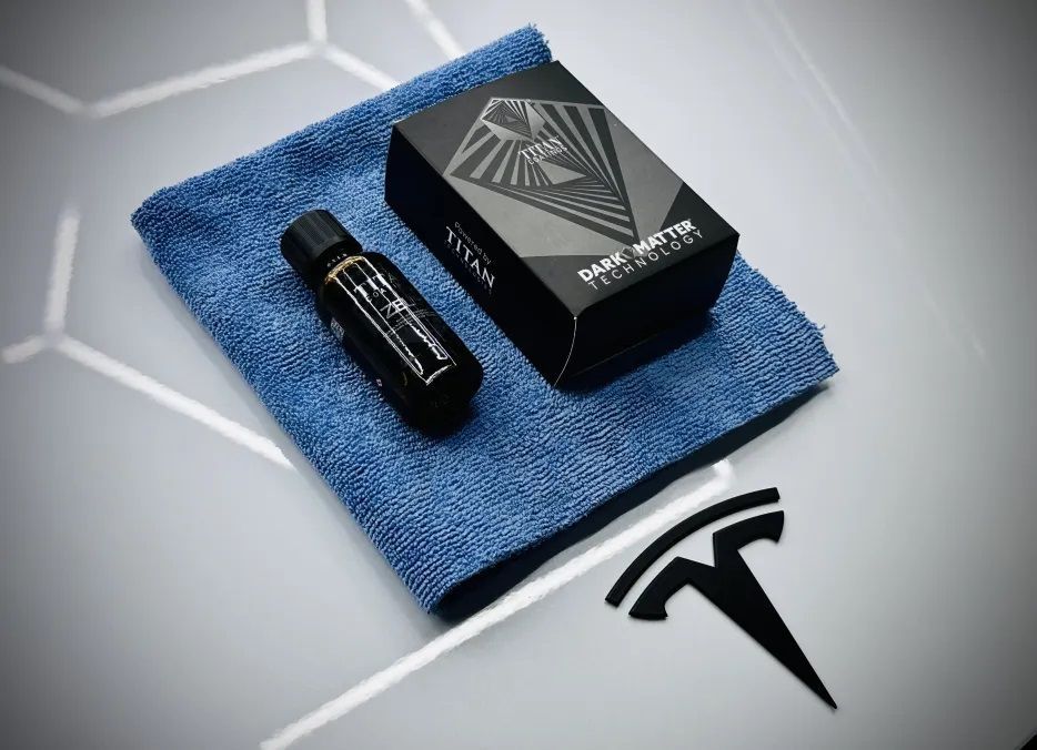 Bouteille et boîte noires avec chiffon en microfibre bleu sur une surface blanche avec un logo Tesla.