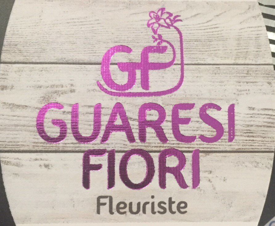Logo de «Guaresi Fiori», fleuriste. Texte rose sur fond bois, avec les initiales «GF» et une icône de fleur.
