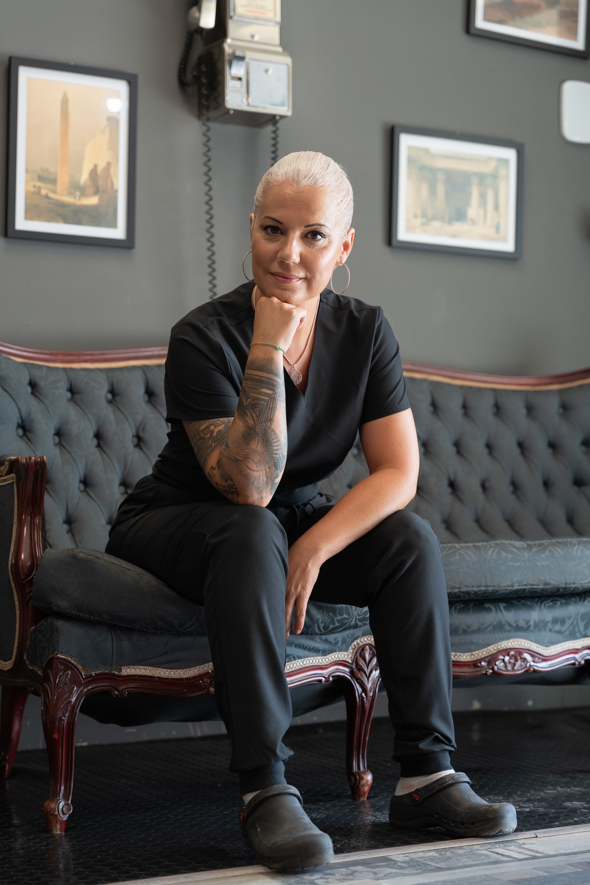 Una mujer está sentada en un sofá con la mano en la barbilla.