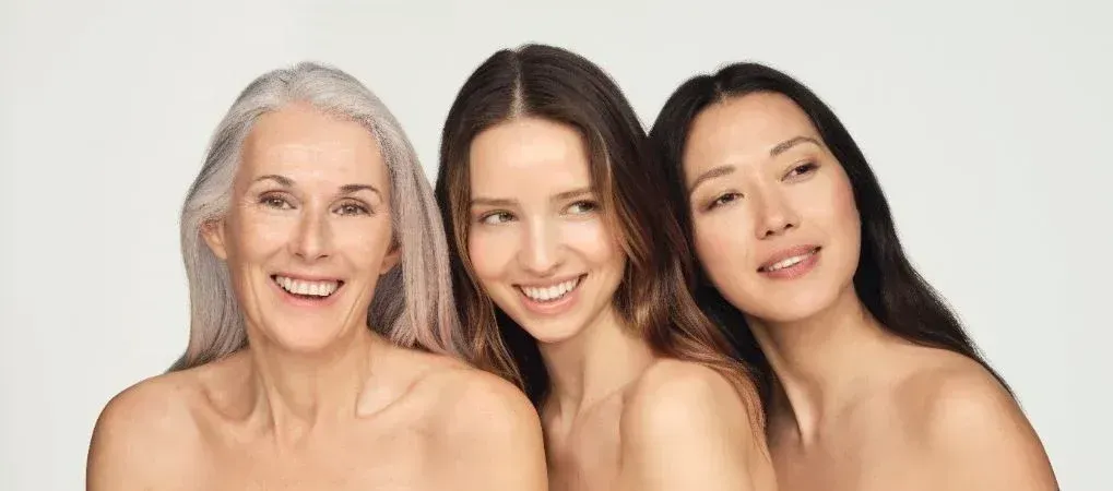 Tres mujeres de diferentes edades posan juntas para una fotografía y sonríen.