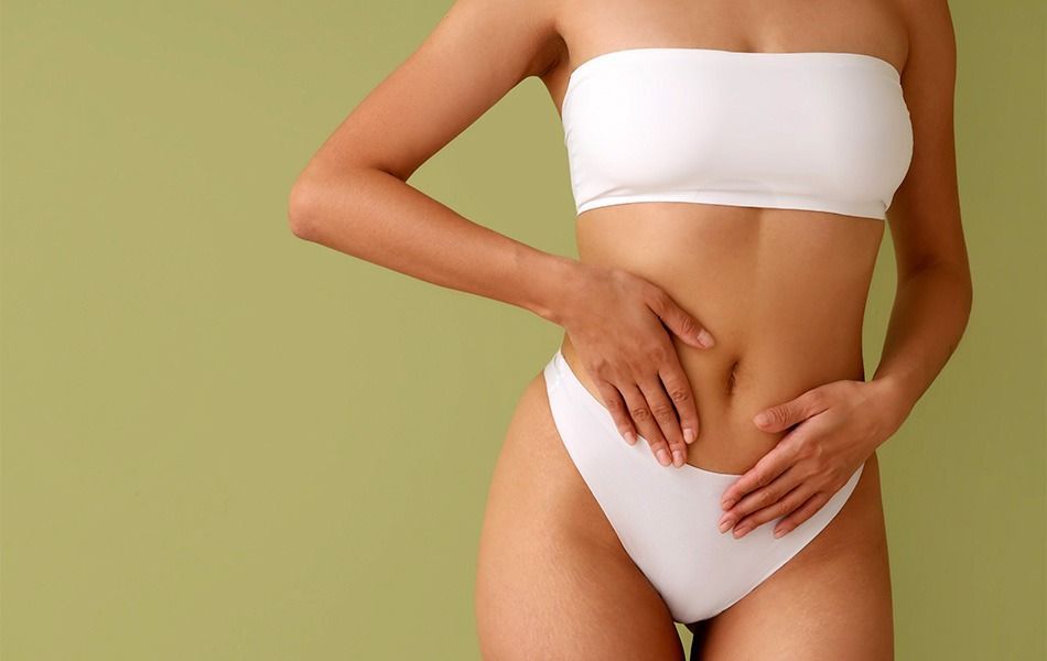 Una mujer en bikini blanco se sostiene el estómago.