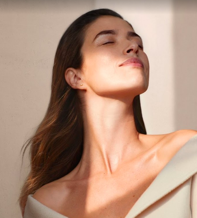 Una mujer con los ojos cerrados lleva un vestido blanco.