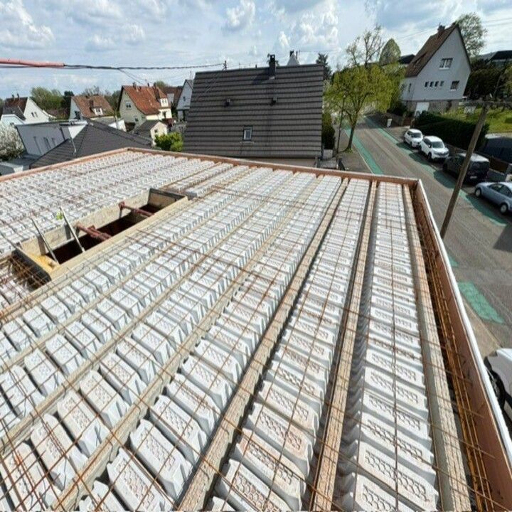 Toiture en construction, isolation et charpente en bois, sous un ciel radieux.