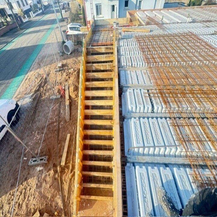 Chantier de construction avec escalier en béton en construction au bord d'une route et de toits d'immeubles