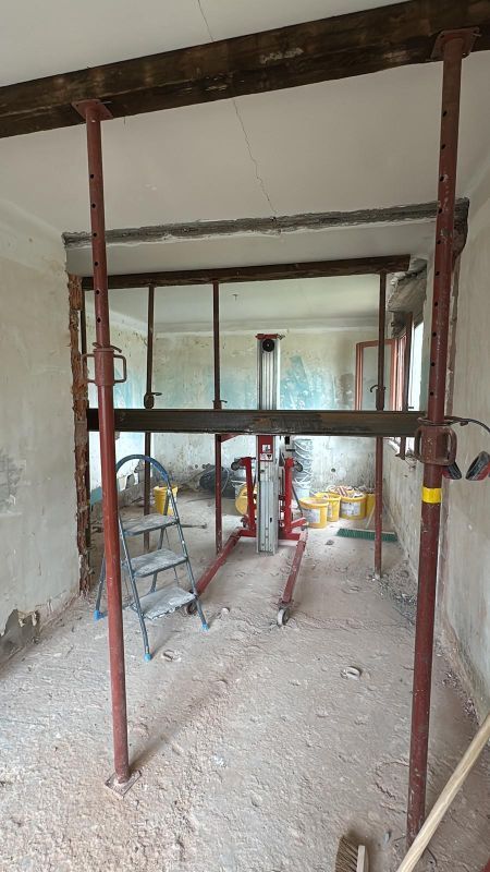 Intérieur en travaux avec échafaudages métalliques rouges et murs et plafond apparents.