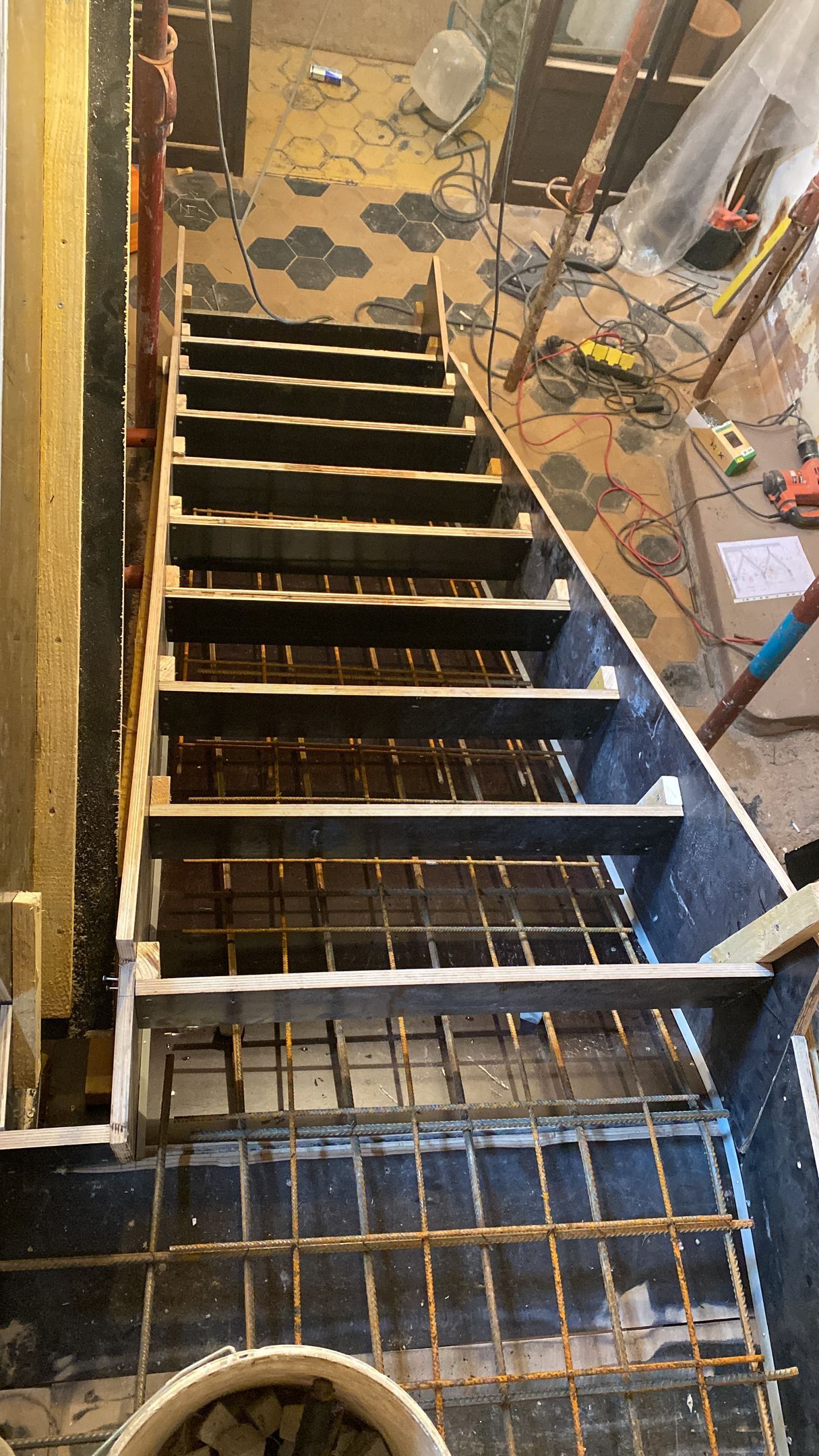 Escalier de chantier avec marches en bois apparentes et murs inachevés.