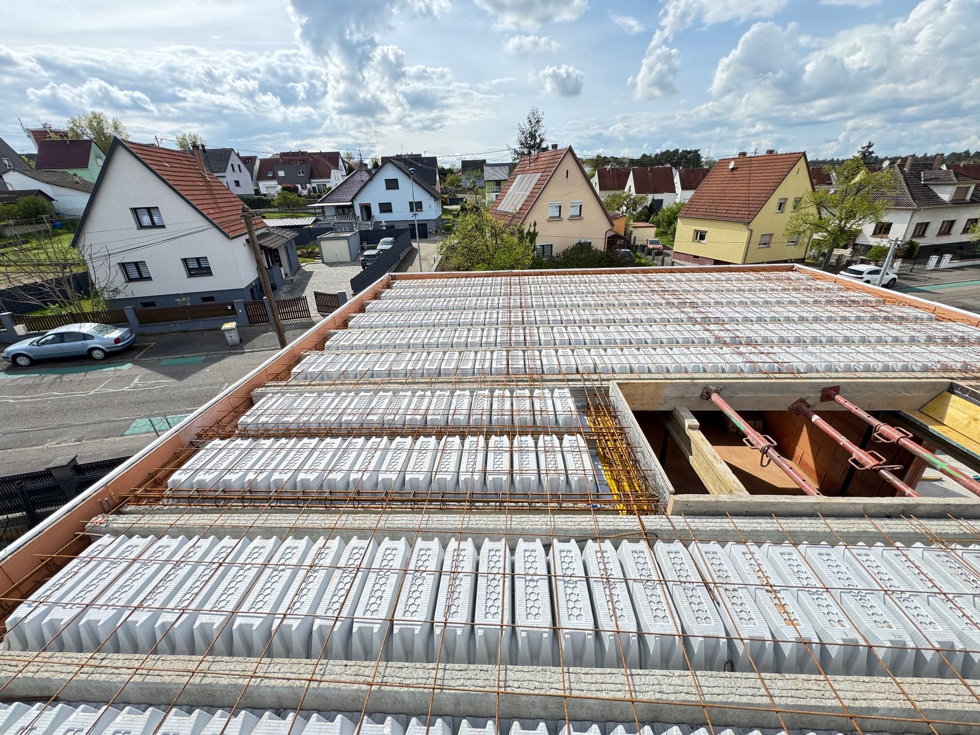 Toiture en construction avec des rangées de panneaux blancs et un quartier de maisons en arrière-plan