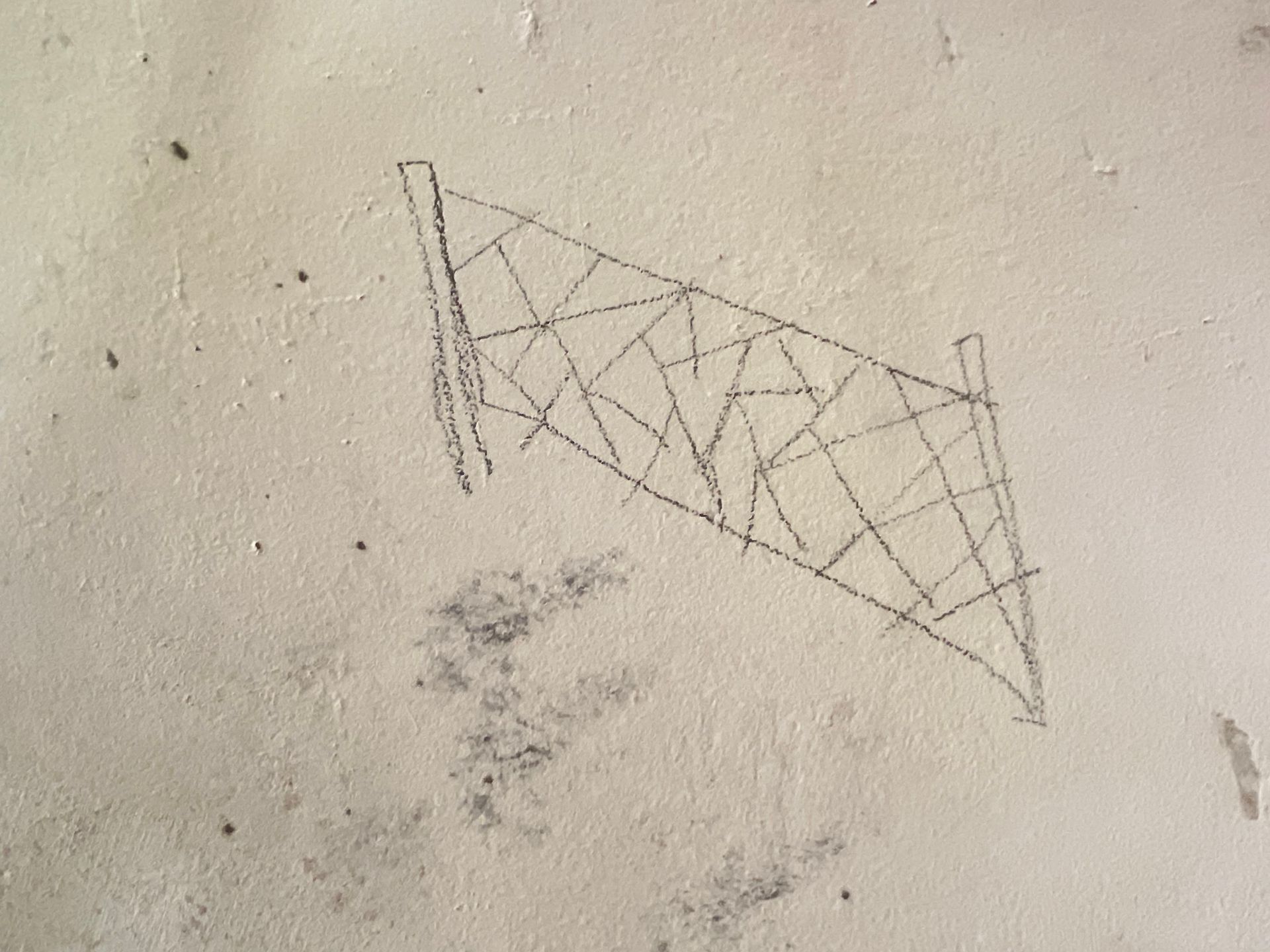 Croquis au crayon estompé représentant une forme triangulaire en forme de filet sur un mur clair.