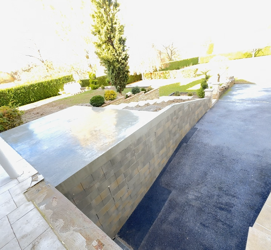 Mur de soutènement extérieur moderne avec jardinière en pierre surélevée et aménagement paysager.