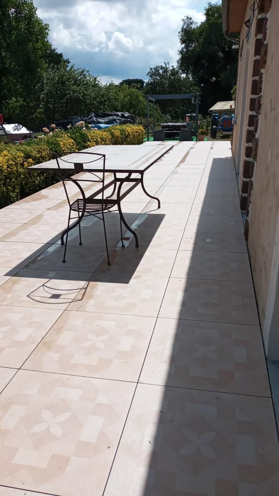 Une table et une chaise de patio en métal sont installées sur une terrasse carrelée.
