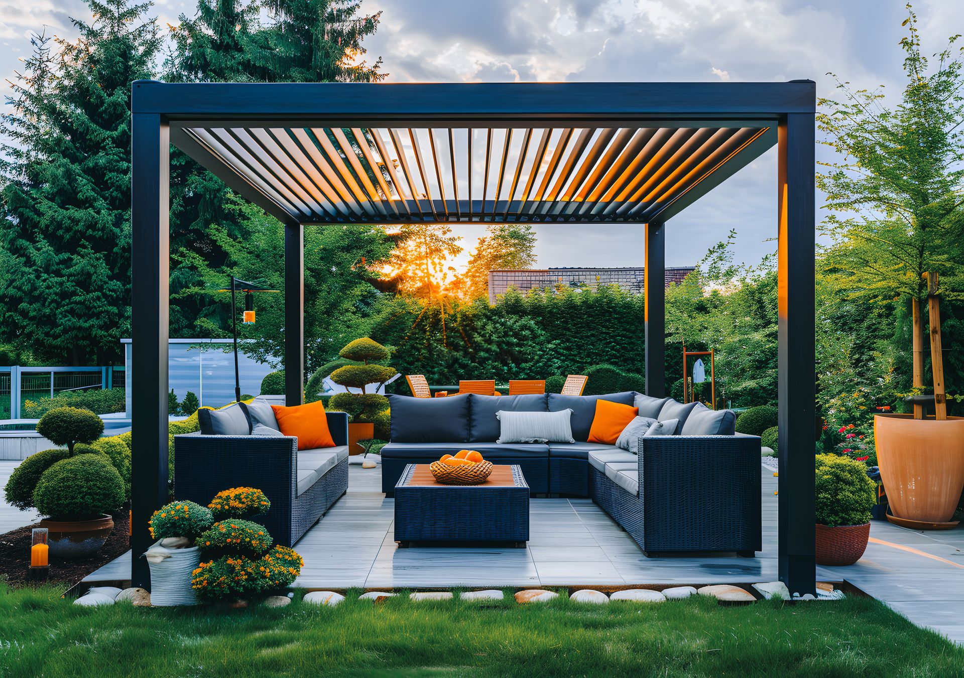 Une pergola noire à persiennes recouvre un coin salon extérieur avec des meubles modulaires noirs.
