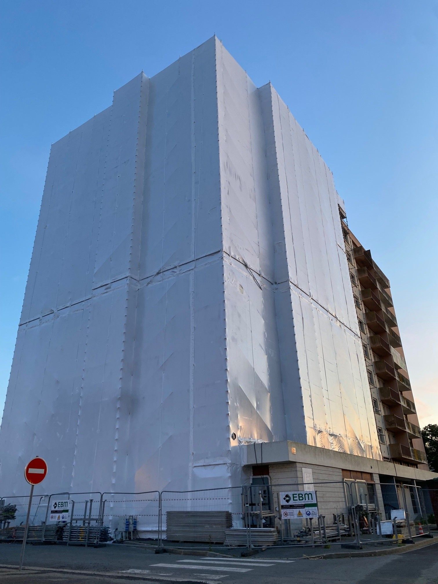 Grand bâtiment enveloppé de bâches de protection.