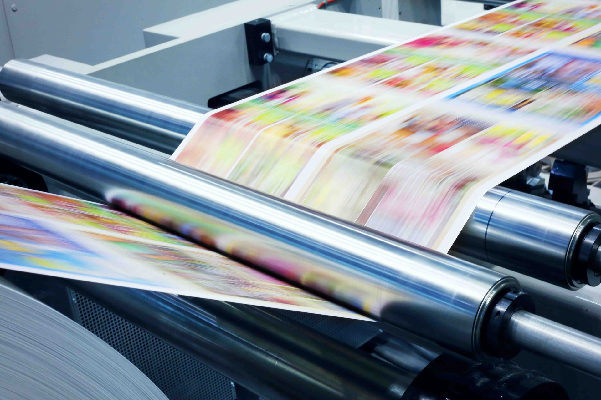 Prensa de imprenta con papel de colores rodando a través de cilindros cromados.