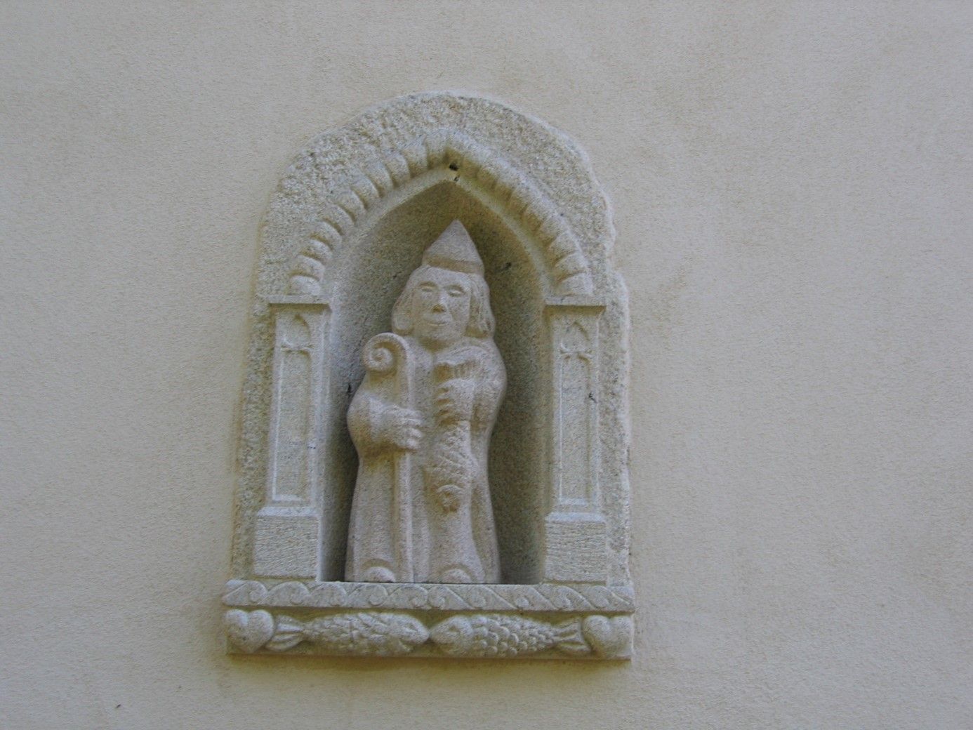 Sculpture murale d'un homme avec un bâton et un chapeau.
