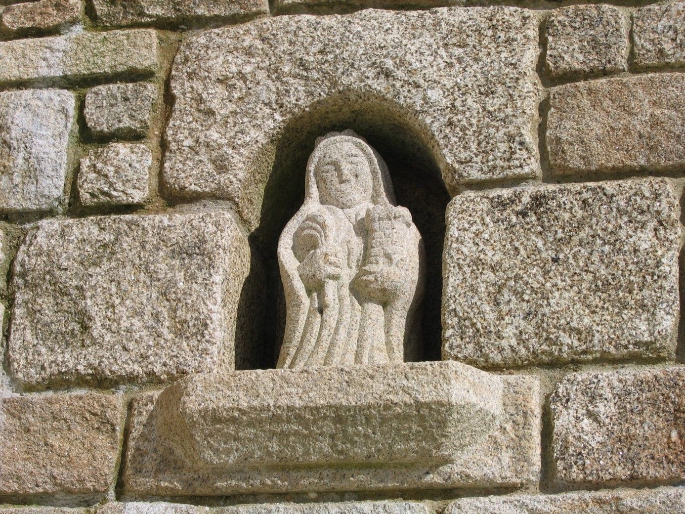 Sculpture encastrée dans un mur en pierre, représentant un personnage.