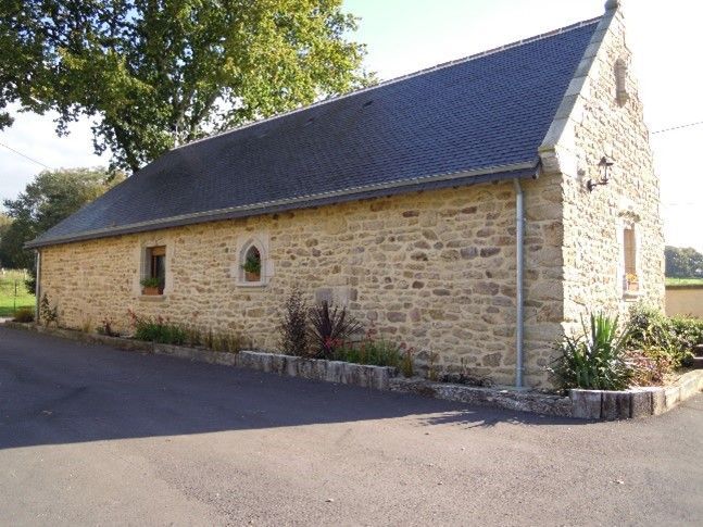 Ancienne bâtisse en pierre rénovée, avec des plantes autour.