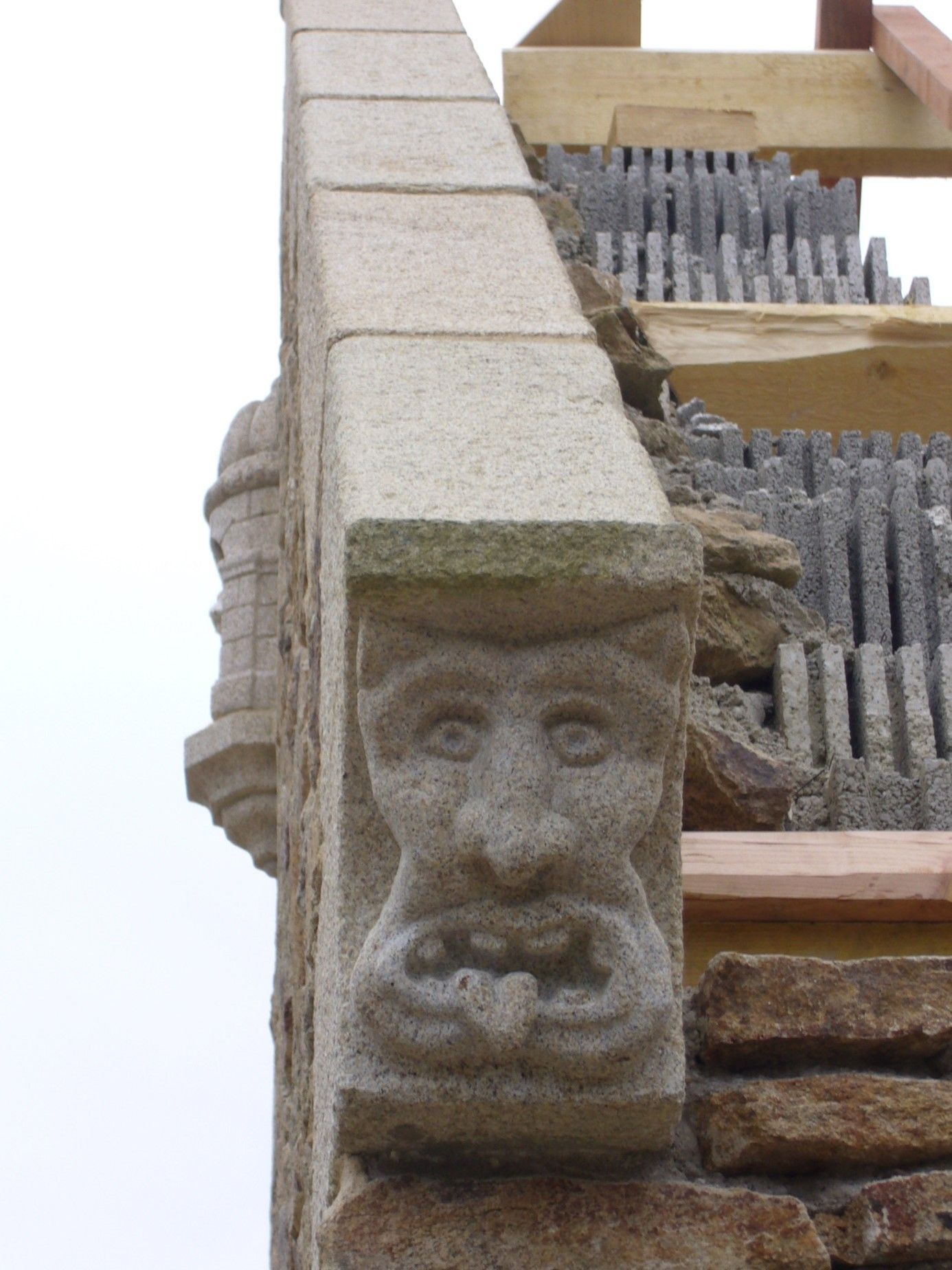 Tête de démon taillé dans une pierre située au bout d'une toiture.