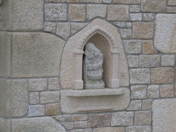 Sculpture d'un personnage en pierre dans un mur en pierre.