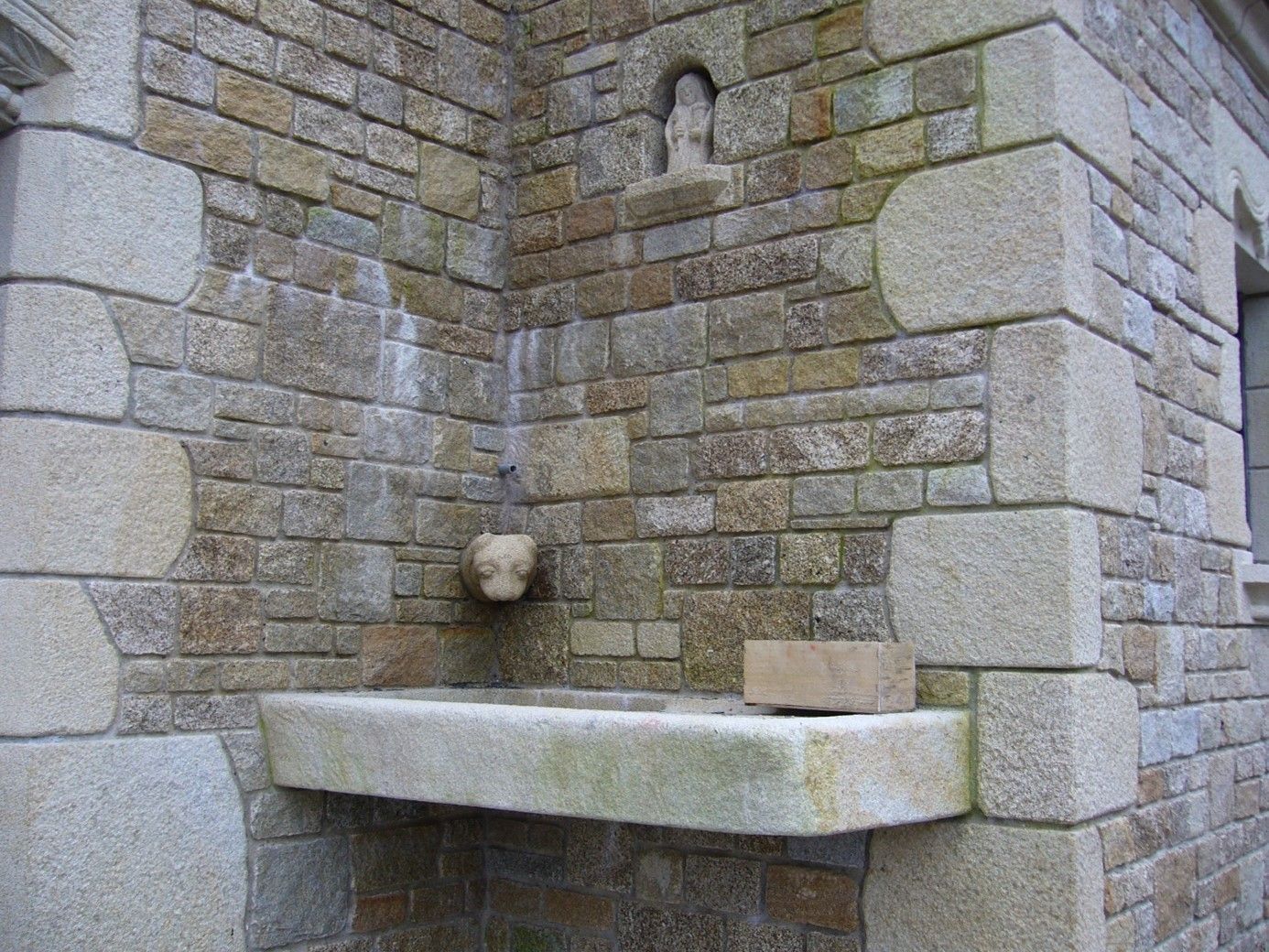 Grande vasque en pierre située dans l'angle d'un bâtiment avec une fontaine.