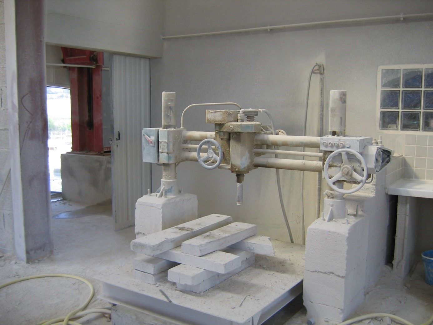 Intérieur de l'entrepôt avec une machine blanche équipée de plusieurs manivelles.