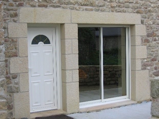 Porte et porte fenêtre blanches ave des tours de pierre.