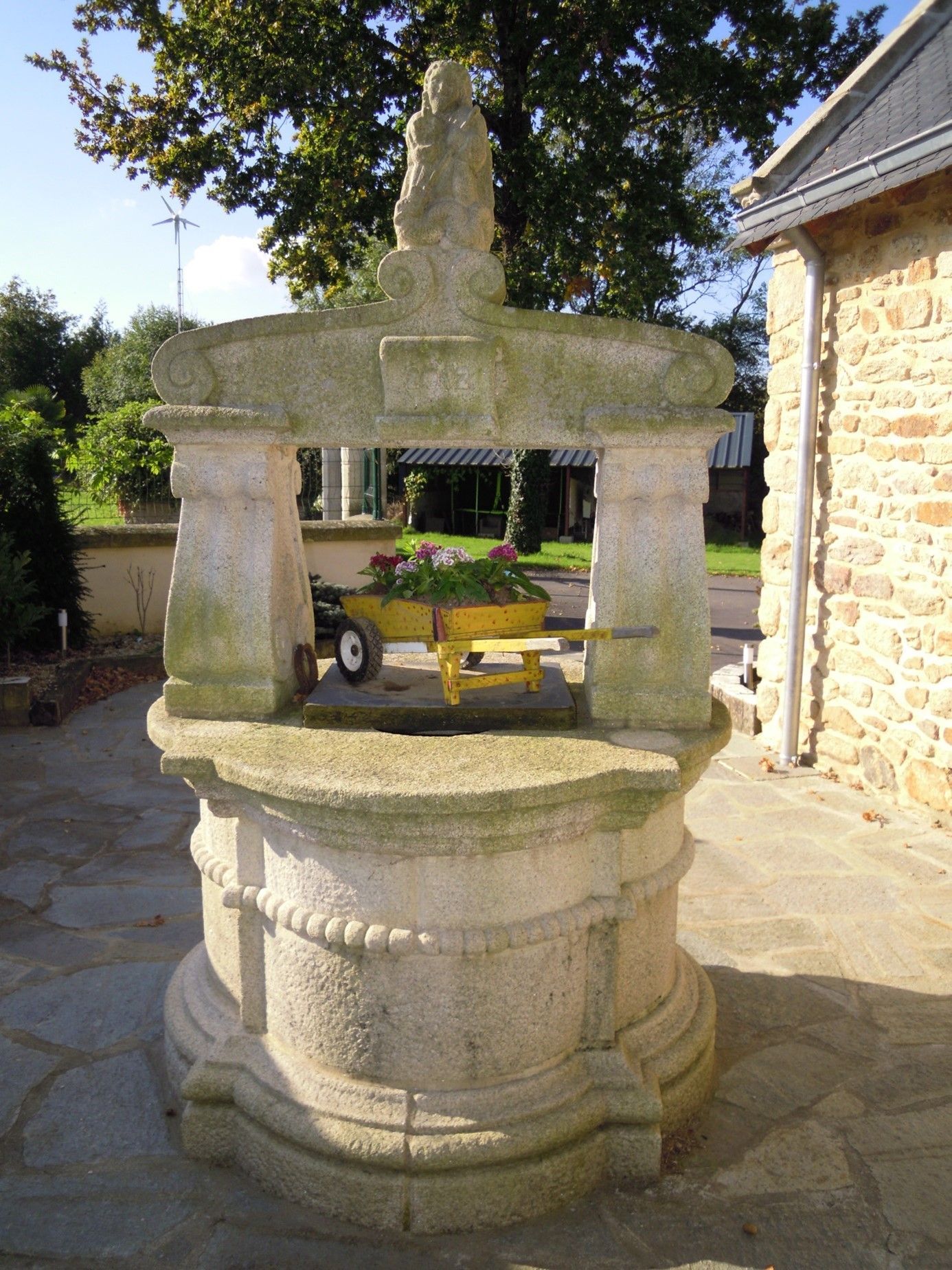Puis en pierre avec une petite charrette jaune remplie de fleurs.