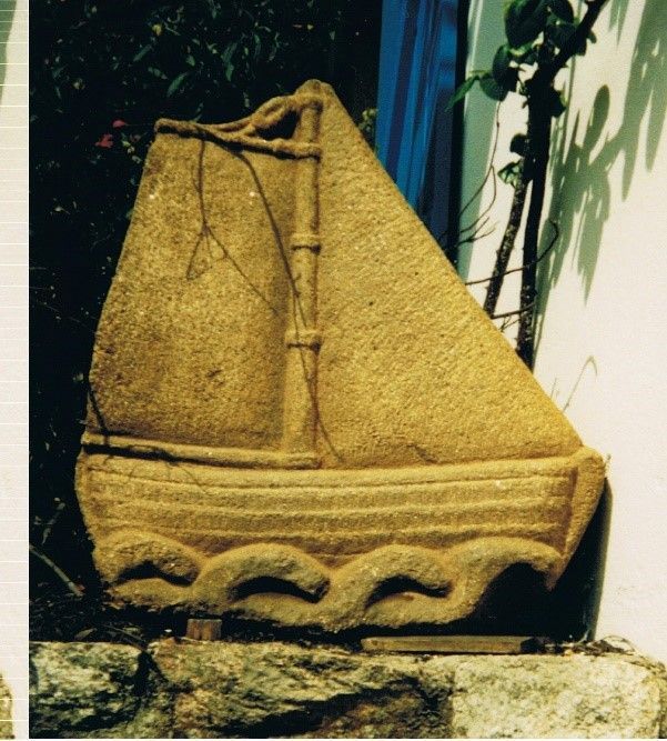 Sculpture d'un voilier en pierre sur des vagues.