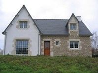 Maison avec une partie en pierre, et l'autre parti avec les tours de fenêtres en pierre.