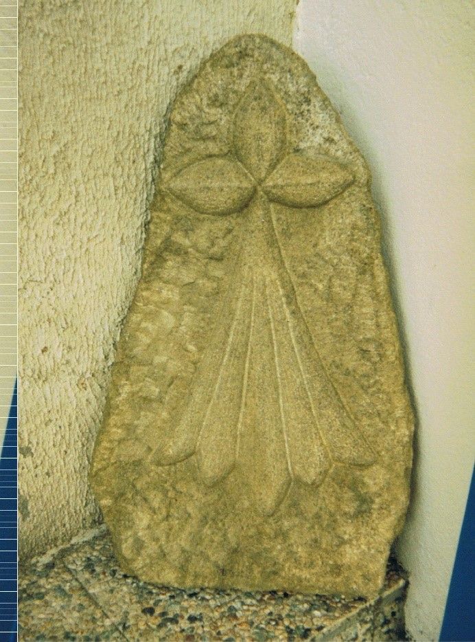 Pierre tombale avec une croix taillée dessus, croix avec des bouts en pointe.