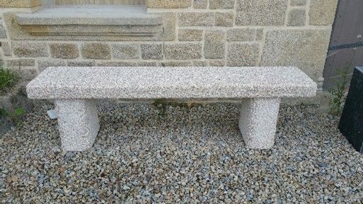 Banc en granit devant un bâtiment en pierre.