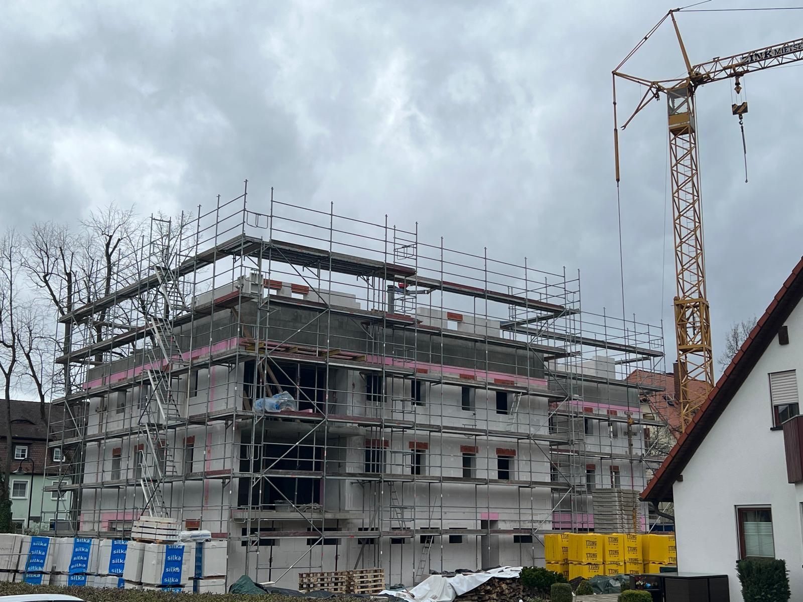 Ein im Bau befindliches Gebäude mit Gerüsten und einem Kran im Hintergrund