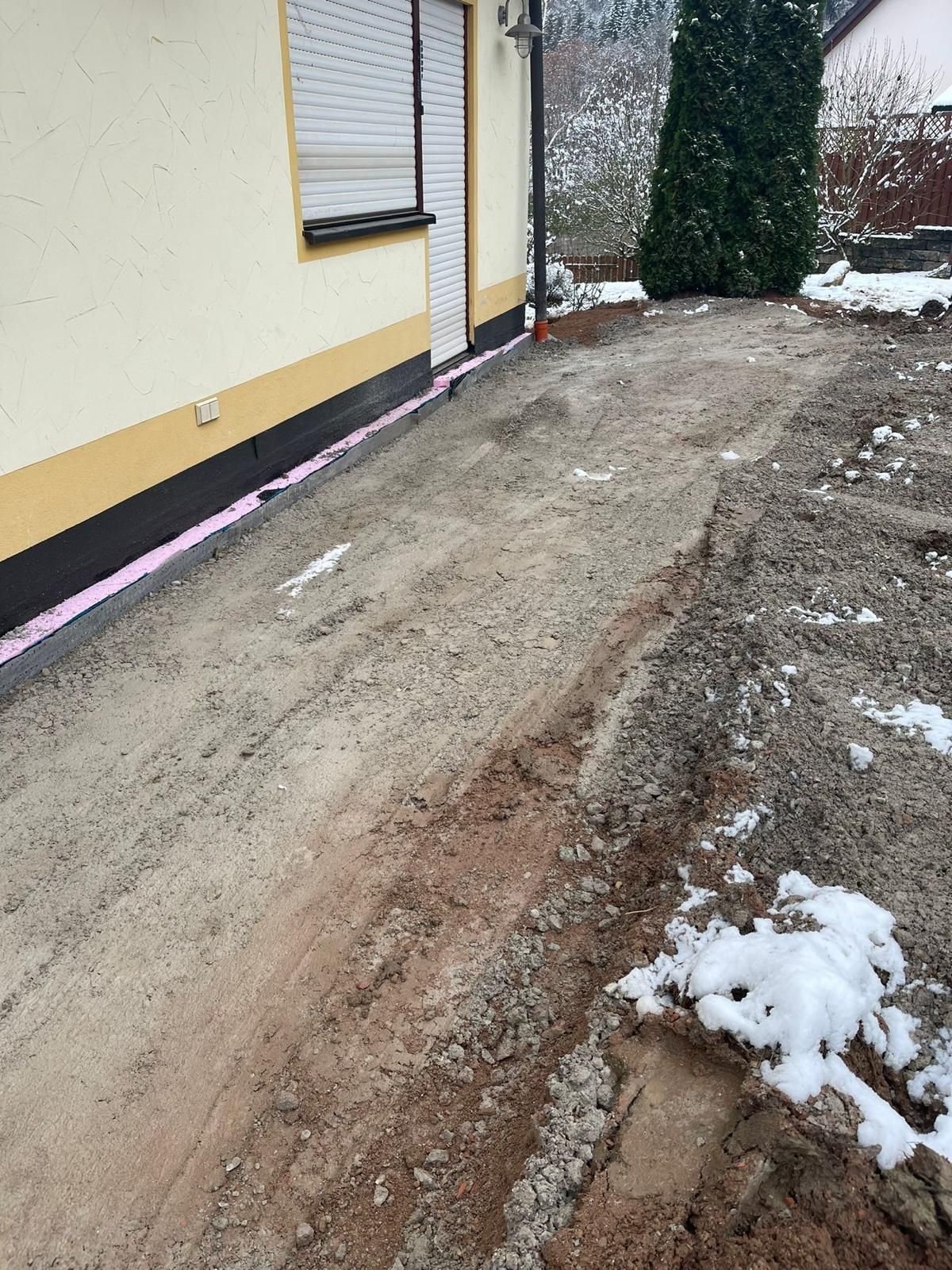 Ein Feldweg vor einem Haus mit Schnee auf dem Boden.