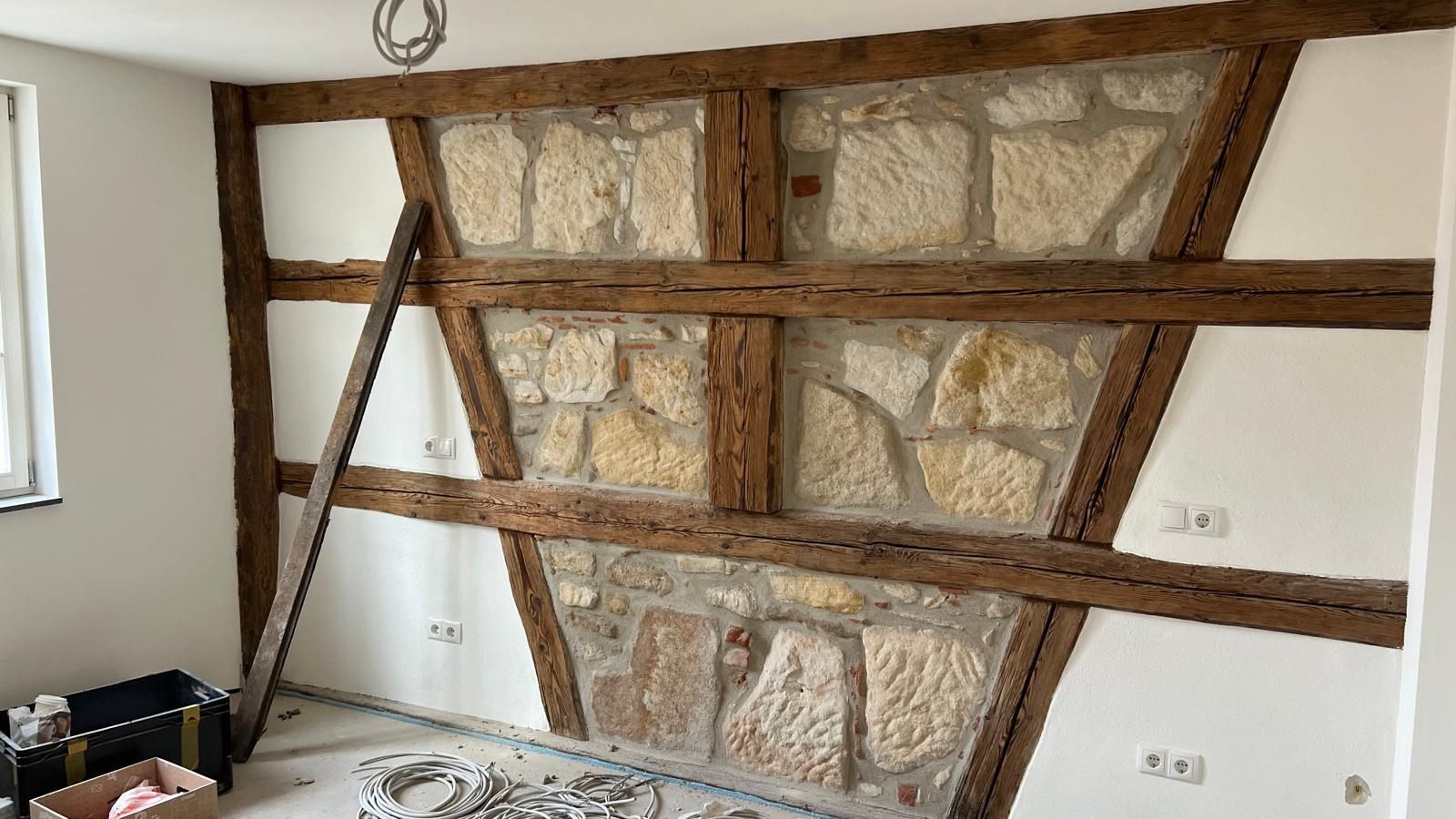 Ein Raum mit Steinwand und Holzbalken.