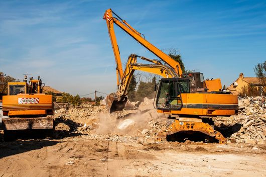 Des excavatrices démolissent des gravats sur un chantier de construction.