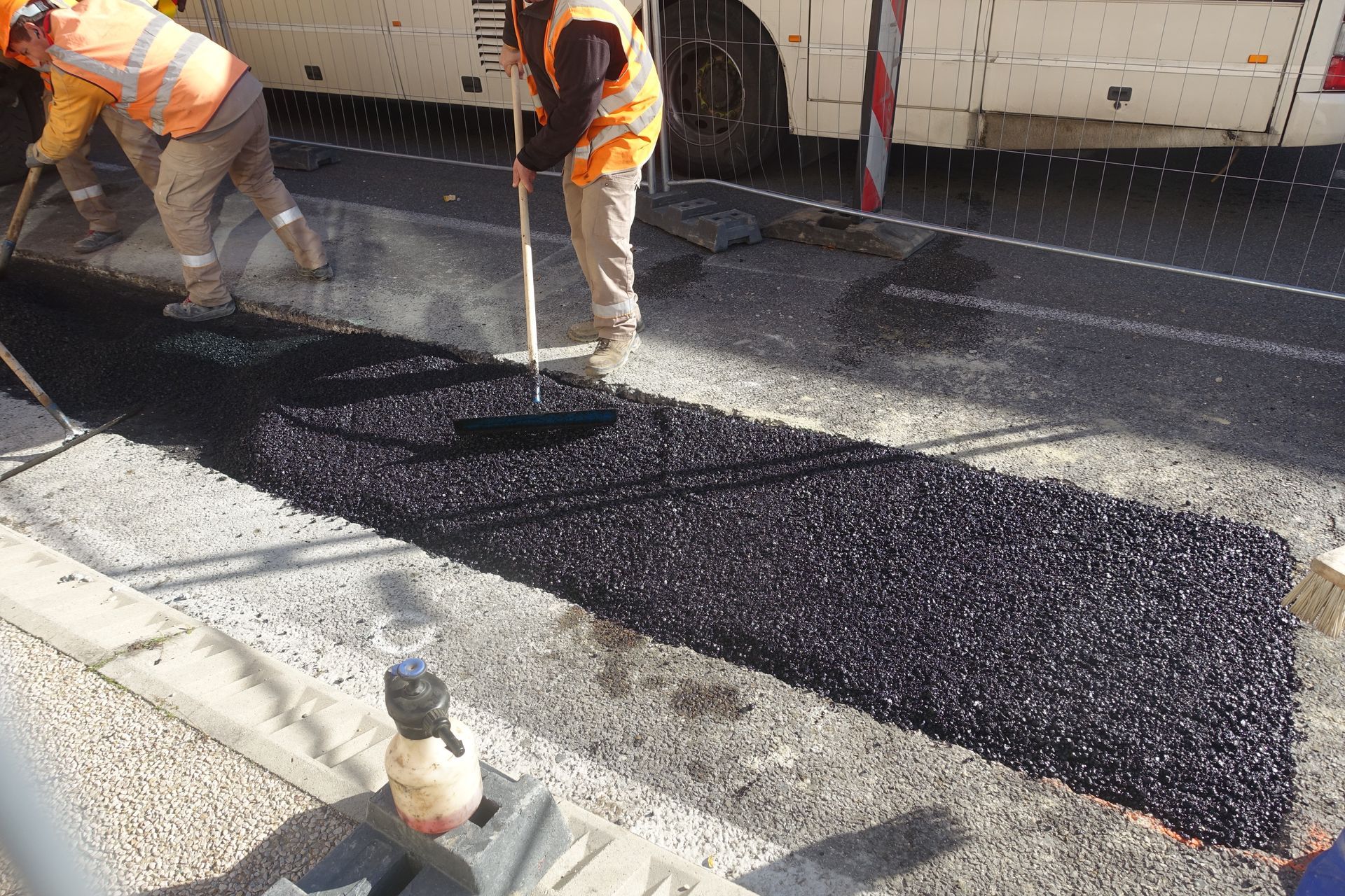 Des ouvriers posent une couche d'asphalte noir frais sur une route.
