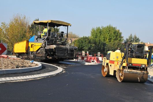 Des rouleaux compresseurs en train de paver un rond-point.