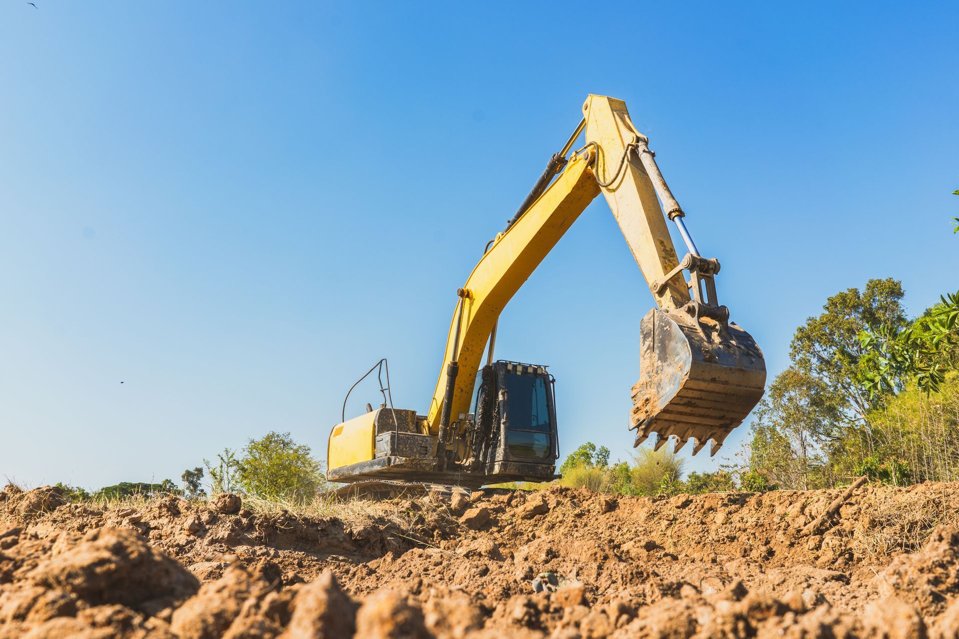Une pelleteuse jaune creuse la terre sur un chantier de construction.