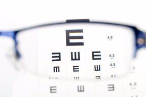 Un par de gafas se encuentra encima de una tabla optométrica.