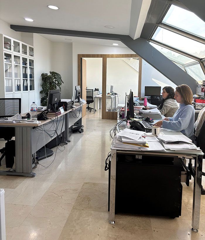 Un grupo de personas están sentadas en escritorios en una oficina.