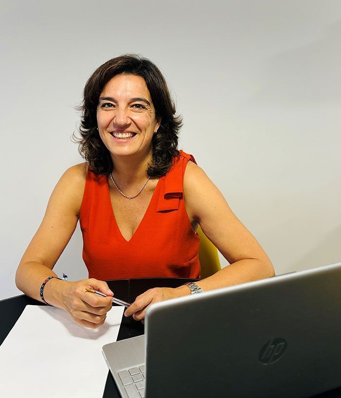 Una mujer está sentada en un escritorio con una computadora portátil HP.