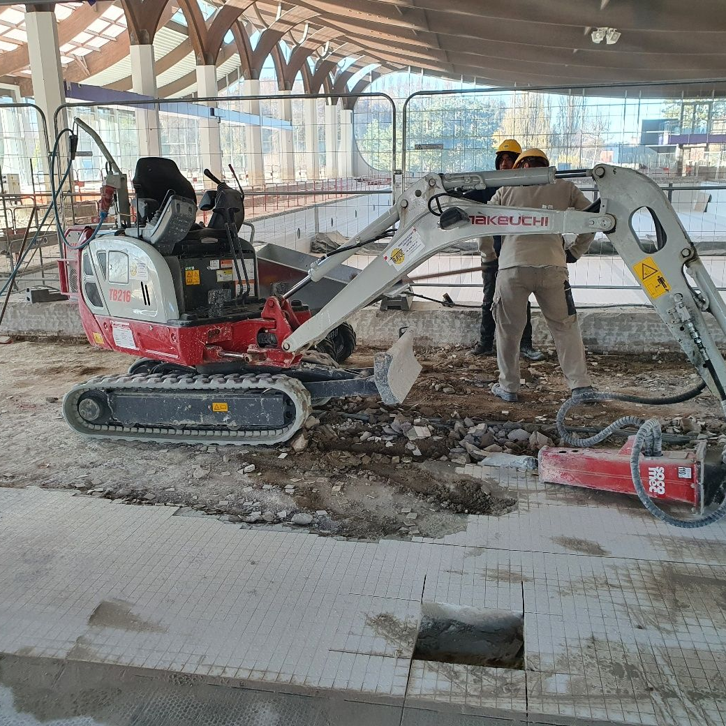 Minipelle sur un chantier à l'intérieur d'une piscine couverte.
