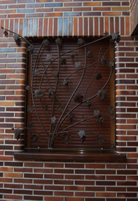 Una pared de ladrillos con una ventana con un diseño de hierro forjado.