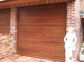 Una estatua de una mujer parada junto a una puerta de garaje de madera.