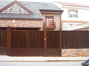 Un coche está aparcado delante de una casa de ladrillo con una valla.