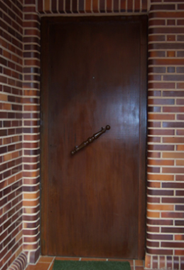 Una puerta de madera con una pared de ladrillos detrás de ella.